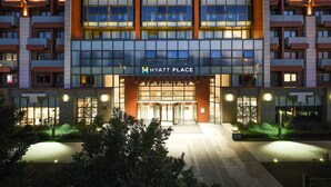 A modern hotel with a glass facade, multiple balconies, and a well-lit entrance. - Hyatt Place Beijing Shiyuan (Yanqing)