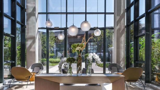 A spacious lobby with a central reception desk, large windows, and modern lighting fixtures. - Hyatt Place Beijing Shiyuan (Yanqing)