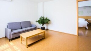 A minimalist room with a grey sofa, a wooden table, and a potted plant. - Greentree Inn Jiaxing Qixing Town Goverment (Jiaxing)