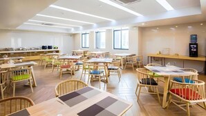 A spacious indoor area with multiple tables and chairs, a coffee machine, and a counter with various items. - Greentree Inn Jiaxing Qixing Town Goverment (Jiaxing)