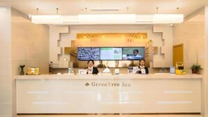 A reception desk at GreenTree Inn with a digital display, a clock, and a sign indicating the name of the establishment. - Greentree Inn Jiaxing Qixing Town Goverment (Jiaxing)