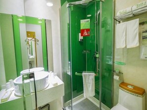 Een badkamer met een douchecabine van glas, een wastafel met spiegel en een toilet.