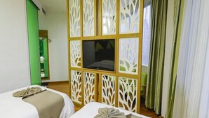 Une chambre d’hôtel avec deux lits, une télévision et un élément de séparation décoratif.