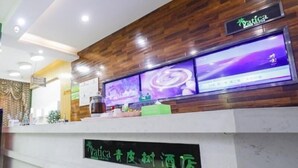 Un comptoir d’accueil avec un panneau décoratif en bois, un écran numérique affichant du contenu et une enseigne indiquant qu’il s’agit d’un hôtel « Yatica ».