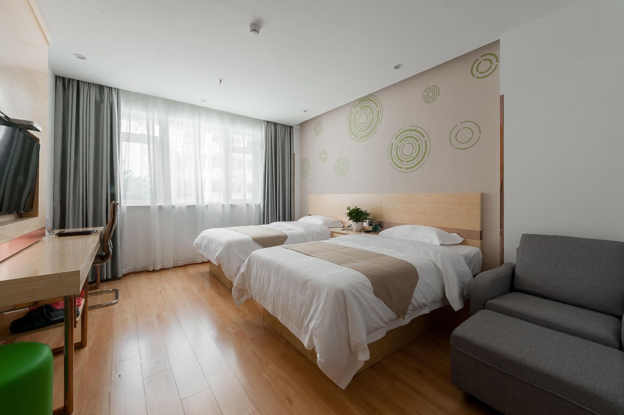 A hotel room with two beds, a desk, a chair, and a sofa.
