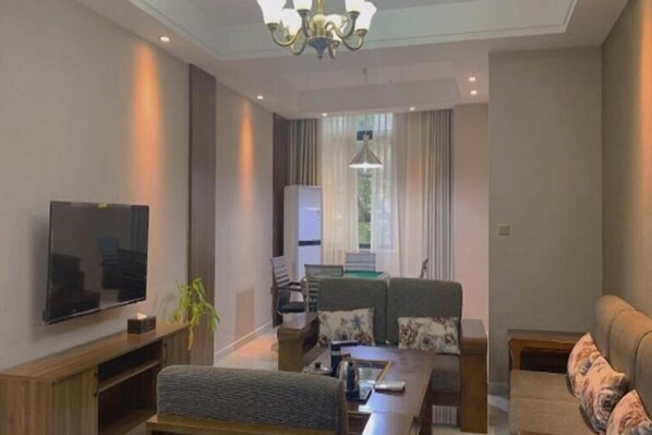Una sala de estar moderna con televisor de pantalla plana, un sofá, una mesa de centro y una araña.