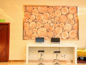 Un área de recepción con un cuadro de pared de troncos de madera, dos taburetes de bar y una barra con dos monitores.