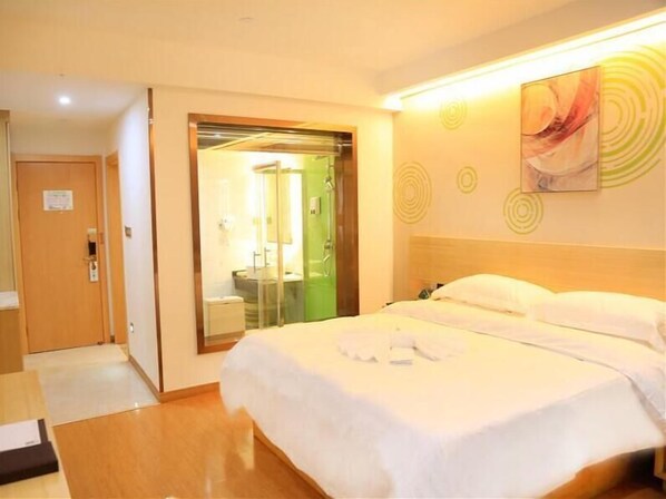 Una habitación de hotel con cama, baño con ducha y puerta que da a otra habitación.