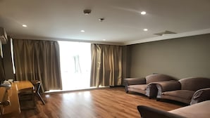 A spacious living room with a wooden floor, two sofas, a dining table with chairs, and a large sliding glass door. - Greentree Inn Jiangyin Zhouzhuang Shiji Avenue Business Hotel (Wuxi)