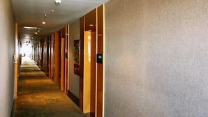 Ein Hotelkorridor mit Teppichboden, Holztüren und einer Schilder mit Zimmernummern.