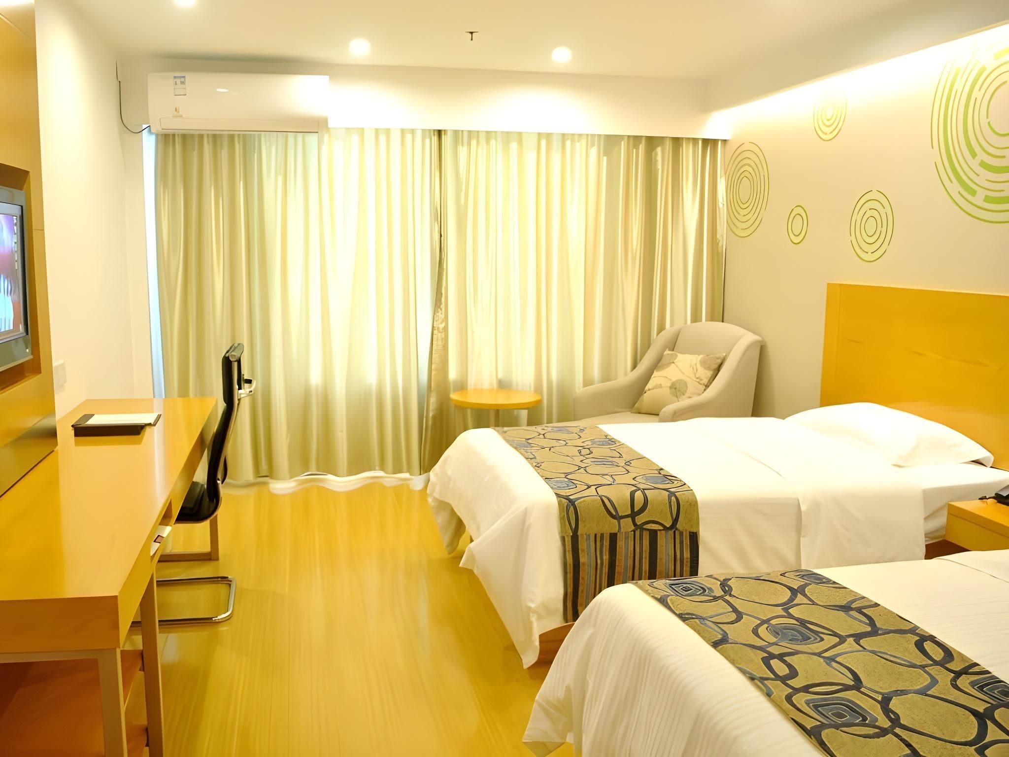 A hotel room with two beds, a desk, a chair, and a TV.