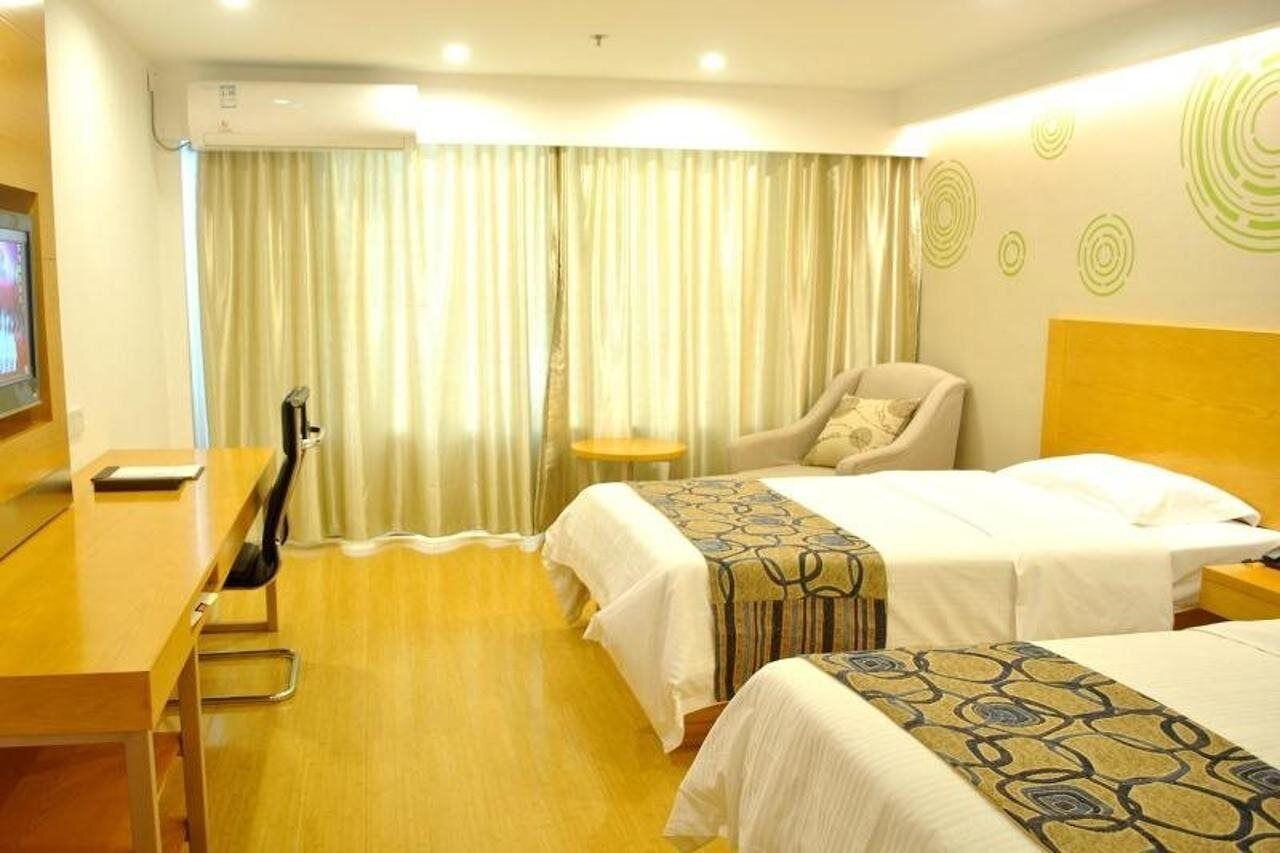 A hotel room with two beds, a desk, a chair, and a TV.