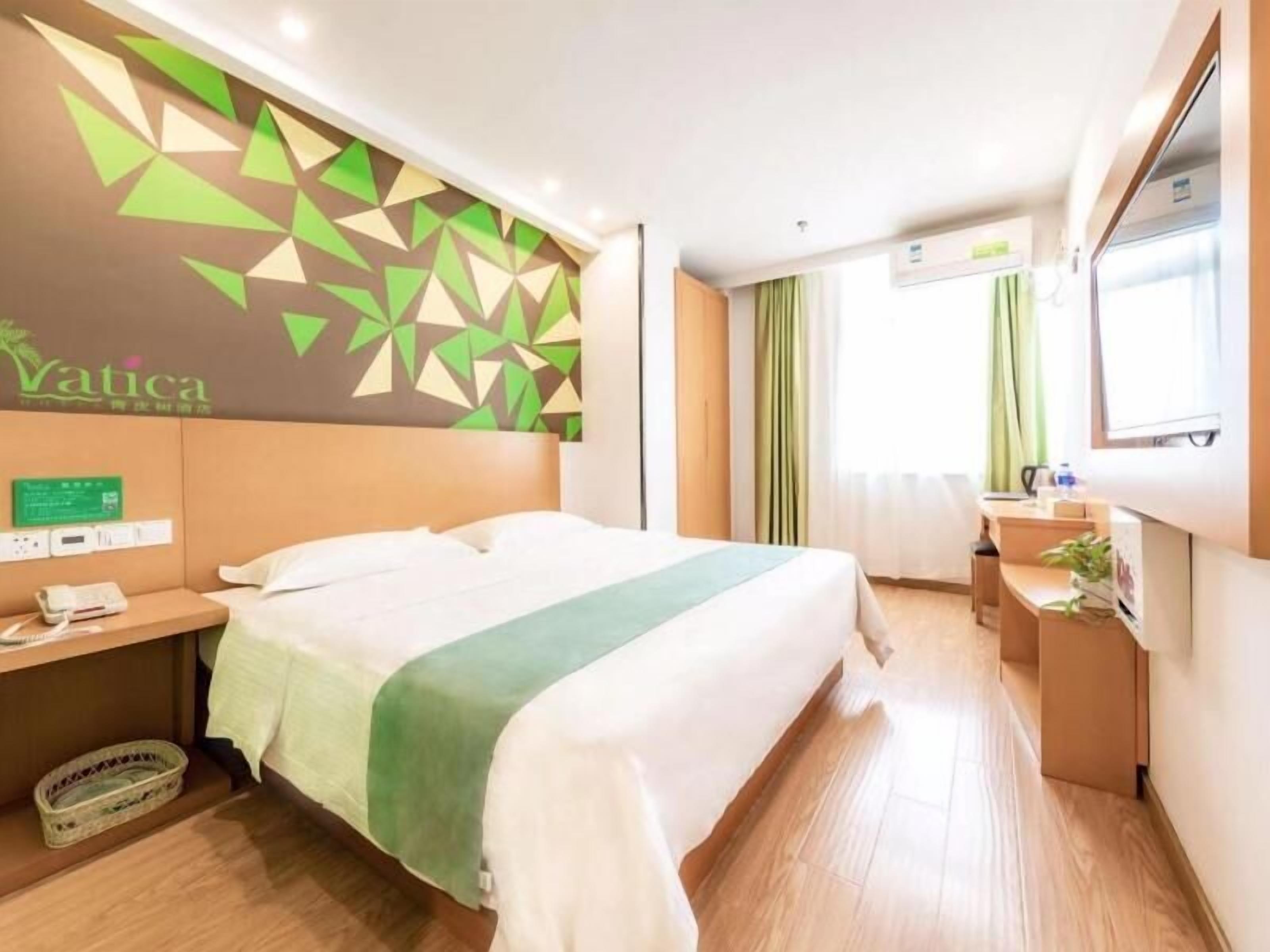 A hotel room with a bed, bedside table, and a wall-mounted TV.