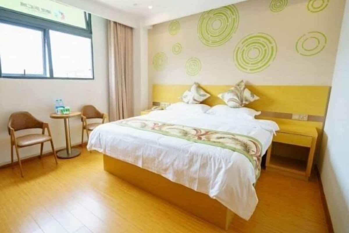A hotel room with a bed, a small table, two chairs, and a nightstand.