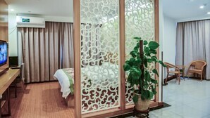 A hotel room with a bed, a TV, a desk, a potted plant, and a decorative screen. - GreenTree Inn (Suzhou Taihu Xukou Town Mudu Lingyan Mountain) (Suzhou)