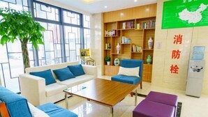 A modern hotel lobby with a sofa, a coffee table, a bookshelf, and a map on the wall. - GreenTree Inn (Suzhou Taihu Xukou Town Mudu Lingyan Mountain) (Suzhou)