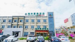 A hotel with a modern facade, multiple floors, and a parking lot with several cars. - GreenTree Inn (Suzhou Taihu Xukou Town Mudu Lingyan Mountain) (Suzhou)
