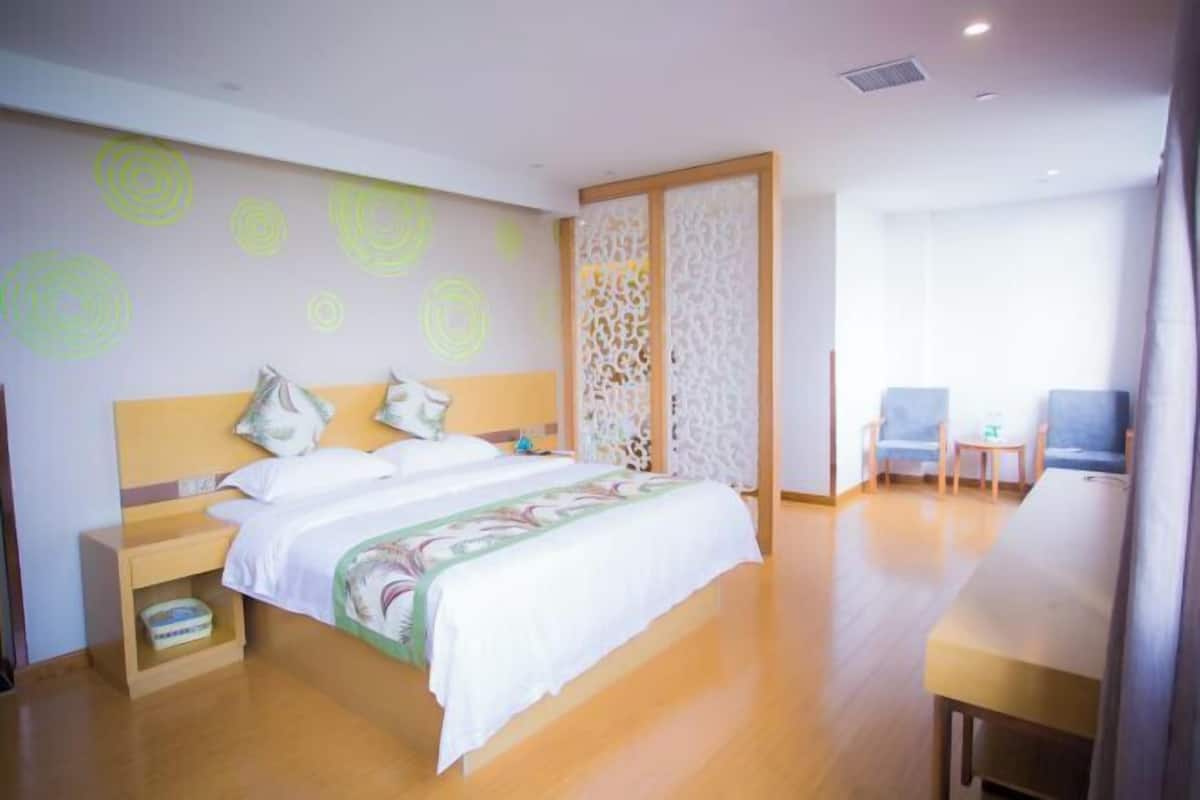 A hotel room with a bed, bedside tables, a desk, and chairs.