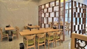 A restaurant with wooden tables and chairs, a tiled floor, and a decorative wall with framed pictures. - GreenTree Inn (Suzhou Taihu Xukou Town Mudu Lingyan Mountain) (Suzhou)