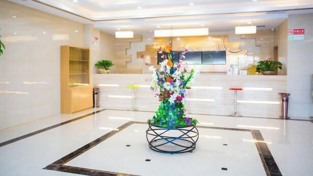 A modern lobby with a reception desk, a decorative floral arrangement, and a seating area. - GreenTree Inn (Suzhou Taihu Xukou Town Mudu Lingyan Mountain) (Suzhou)