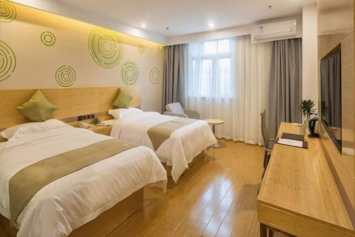A hotel room with two beds, a wooden desk, a small table, and a TV.