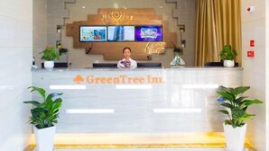 A reception desk with a digital screen displaying images, a receptionist, and potted plants. - Greentree Inn Cixi Zhouxiang Town Jiayue Plaza (Ningbo)