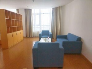 A living room with a sofa, a coffee table, and a bookshelf. - Greentree Inn Cixi Zhouxiang Town Jiayue Plaza (Ningbo)