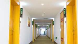 A hotel corridor with yellow doors, green directional signs, and a carpeted floor. - Greentree Inn Cixi Zhouxiang Town Jiayue Plaza (Ningbo)