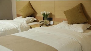 Quarto de hotel com duas camas, uma mesa de cabeceira com telefone e um vaso de flores, e uma cabeceira de madeira.