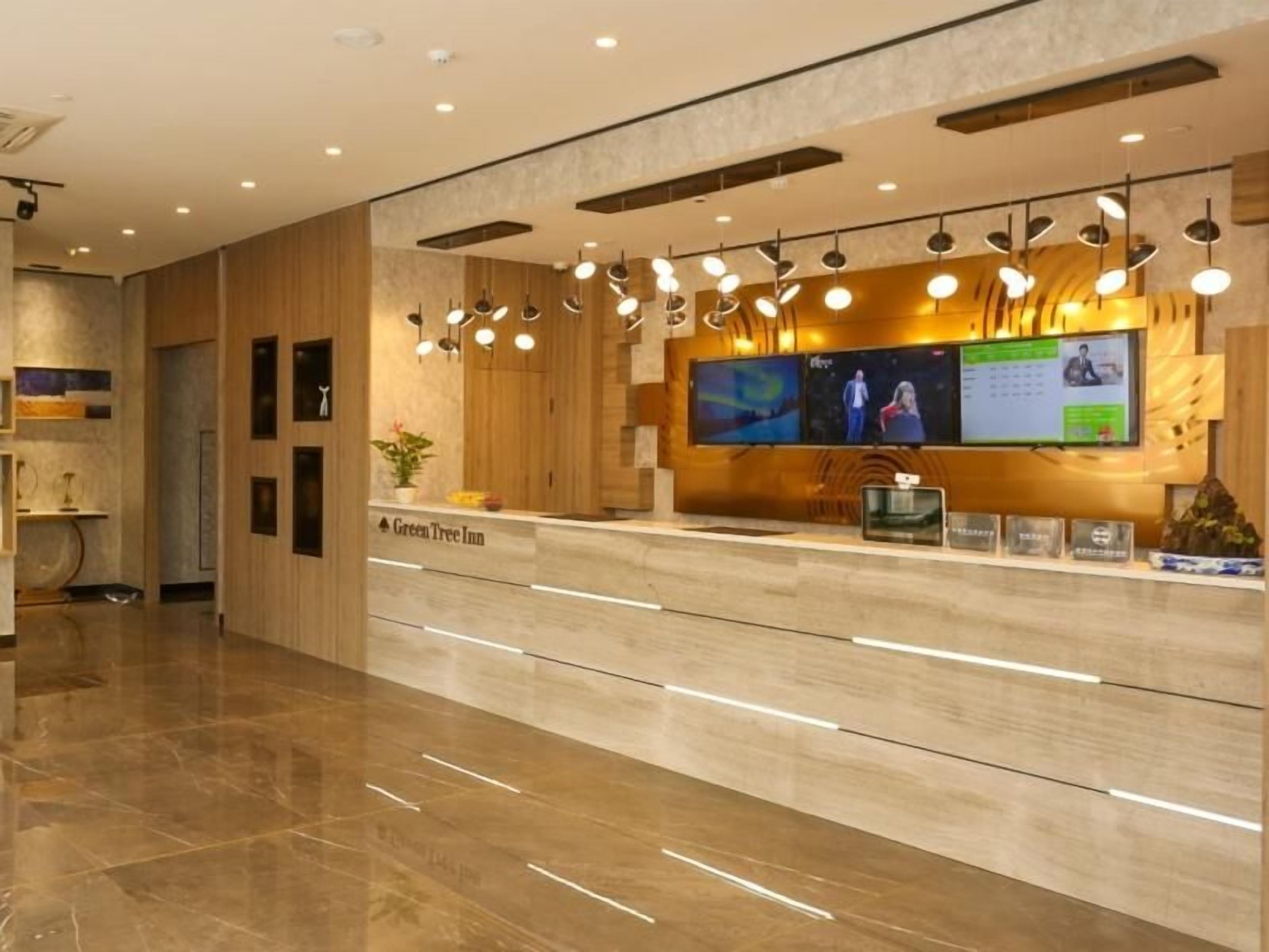 A reception desk with a wooden finish, a flat-screen TV, and a digital display.