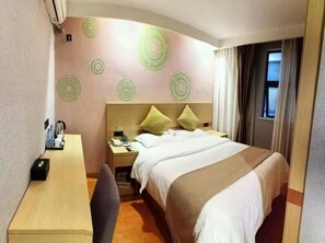 A hotel room with a bed, a desk, a chair, a nightstand, and a wall with circular patterns. - Greentree Inn Suzhou Changshu Southeast Development Zone Southeast Avenue (Suzhou)