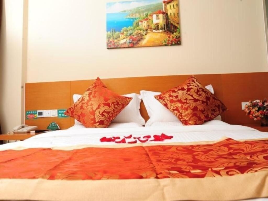 Habitació d'hotel amb un llit, dos almoiners estampats, un quadre a la paret i una tauleta de nit amb un telèfon.