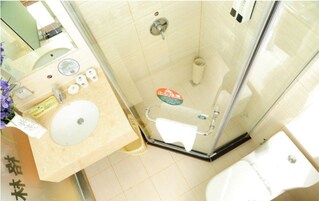 Un baño con cabina de ducha de vidrio, lavabo con espejo e inodoro.