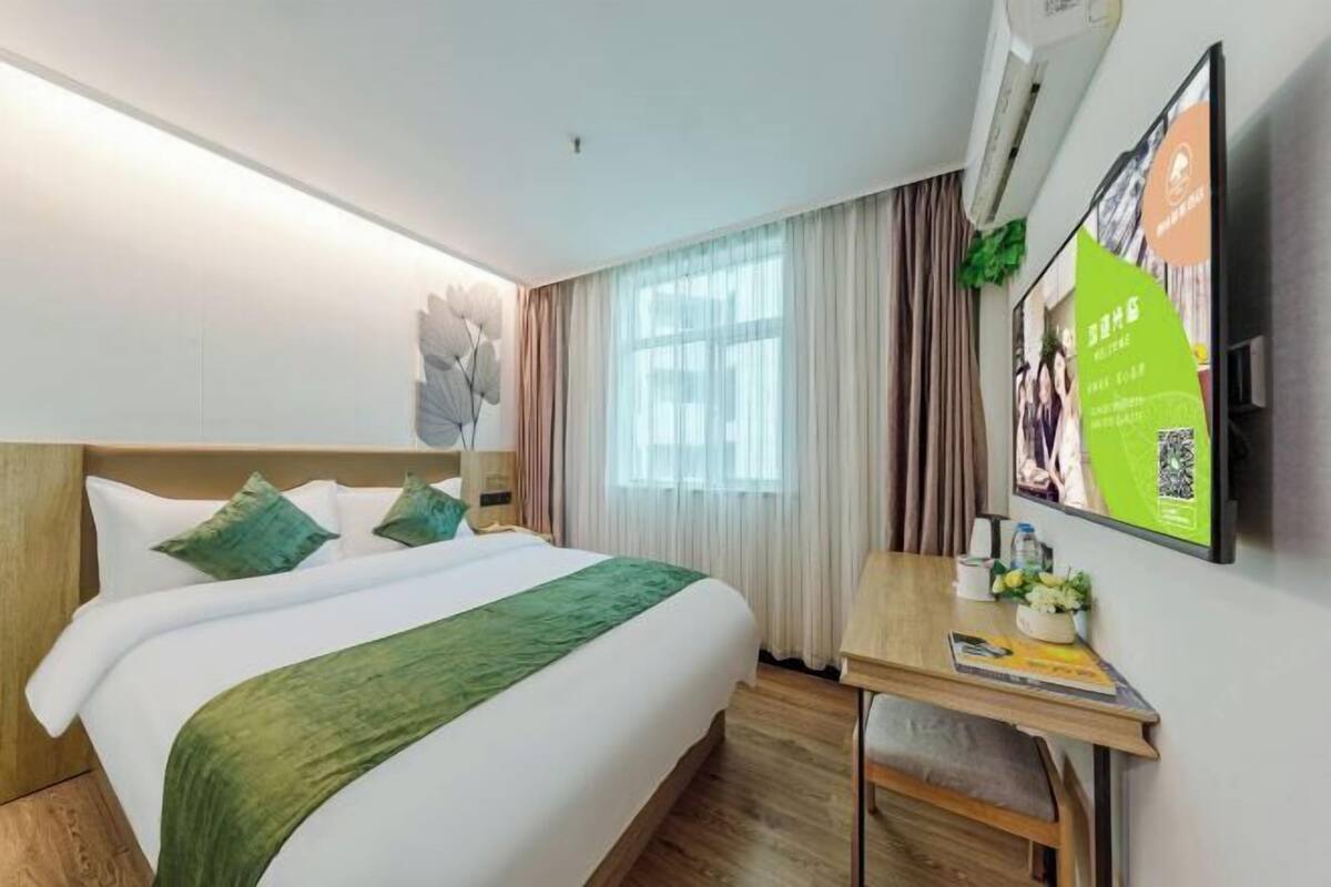 Une chambre d’hôtel avec un lit, un bureau, une télévision et une fenêtre avec des rideaux.
