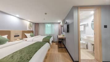 A hotel room with two beds, a desk, a mirror, and a bathroom visible through an open door.