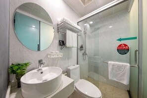 Une salle de bain moderne avec un grand miroir rond, un lavabo, des toilettes et une douche séparée par une paroi de verre.