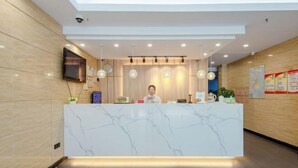A reception desk with a marble top, a flat-screen TV mounted on the wall, and a ceiling with recessed lighting. - GreenTree Inn (Shanghai Xuhui Xujiahui Yishan Road Metro Station) (Shanghai)