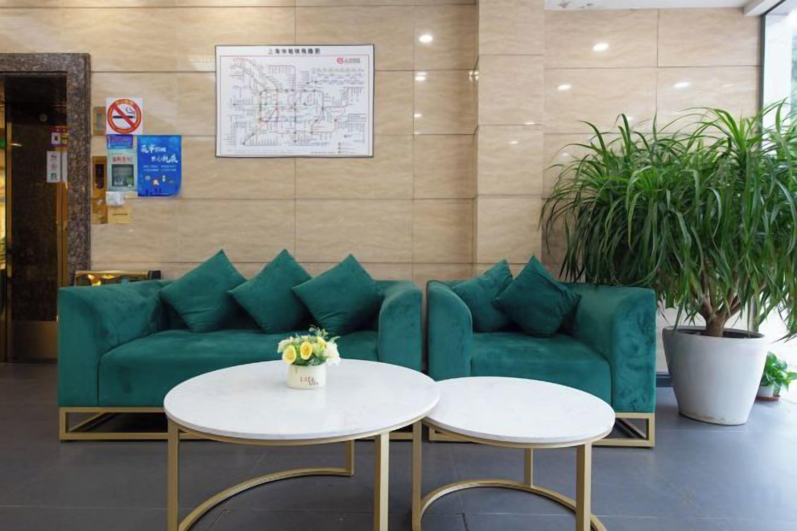 A reception area with a green sofa, two round tables, a potted plant, and a wall map.