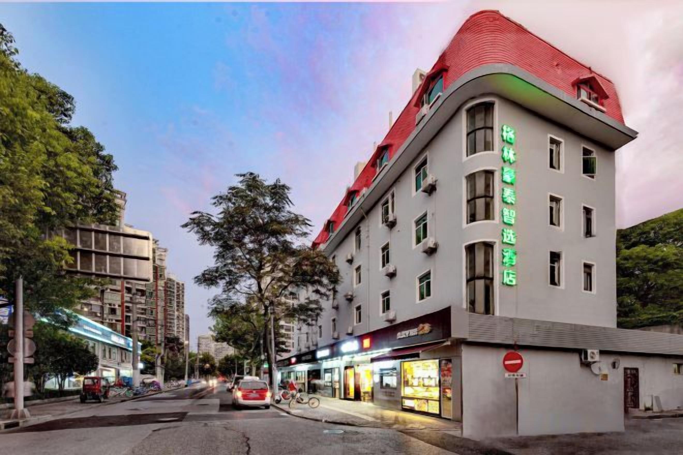 Um hotel com telhado vermelho, vários andares e uma placa indicando que é um hotel.