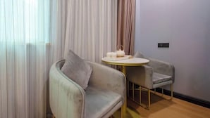 A modern room with a sofa, a small round table, and a chair. - GreenTree Inn (Shanghai Xuhui Xujiahui Yishan Road Metro Station) (Shanghai)