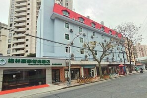 A multi-story building with a red roof, a storefront with a sign, and a row of bicycles parked outside. - GreenTree Inn (Shanghai Xuhui Xujiahui Yishan Road Metro Station) (Shanghai)