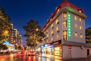 A hotel with multiple floors, a red roof, and illuminated signage. - GreenTree Inn (Shanghai Xuhui Xujiahui Yishan Road Metro Station) (Shanghai)