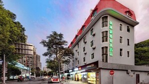 A hotel with a red roof and multiple windows, located on a street with trees and other buildings. - GreenTree Inn (Shanghai Xuhui Xujiahui Yishan Road Metro Station) (Shanghai)