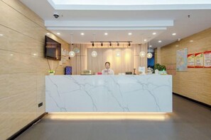 A reception desk with a marble top, a flat-screen TV, and a wall-mounted security camera. - GreenTree Inn (Shanghai Xuhui Xujiahui Yishan Road Metro Station) (Shanghai)
