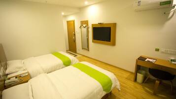 A hotel room with two beds, a desk, a chair, a mirror, and a television.