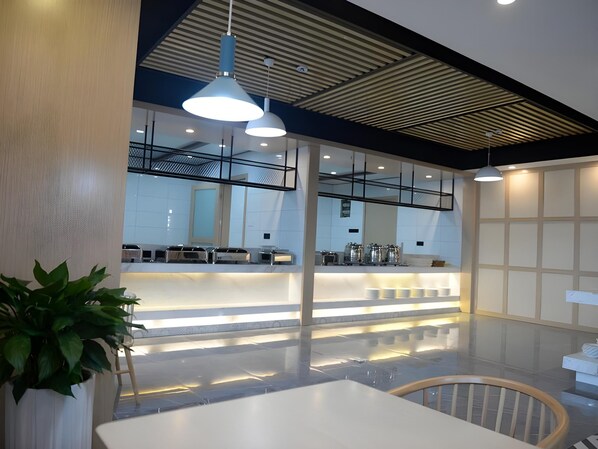 A modern interior with a reception desk, seating area, and pendant lighting.