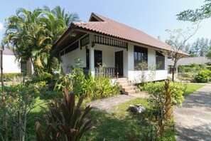 A two-story house with a tiled roof, a porch with a railing, and a garden with various plants. - Chaiyo Resort Phuket by Zuzu (Wichit)