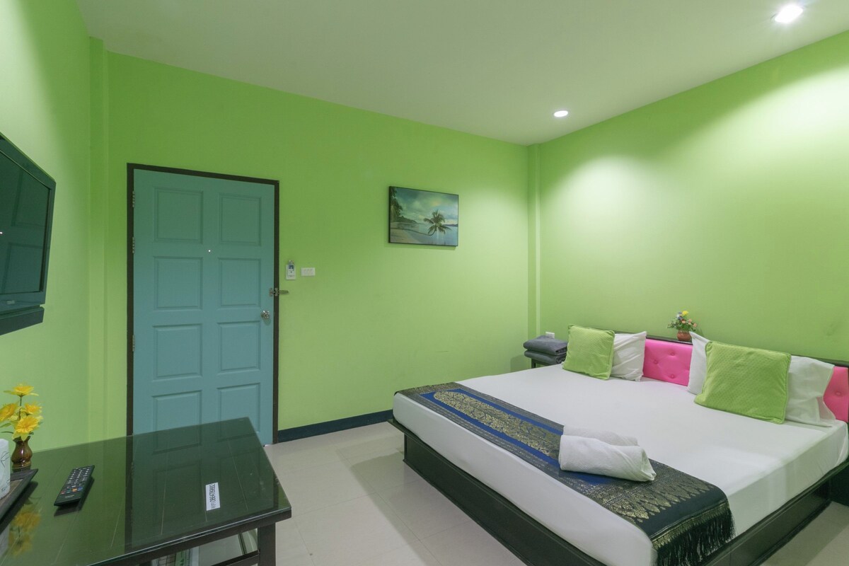 A room with a bed, a desk, a door, and a painting on the wall.