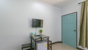 A small room with a desk, a television mounted on the wall, a door, and a curtain. - Chaiyo Resort Phuket by Zuzu (Wichit)