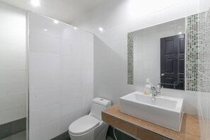 A bathroom with white tiles, a toilet, a sink, and a mirror. - Chaiyo Resort Phuket by Zuzu (Wichit)